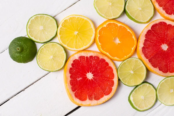Toranja limão, tangerina, laranja e rosa sobre madeira branca — Fotografia de Stock