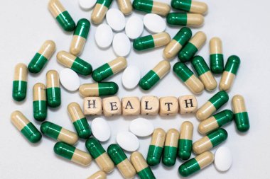 Haplar ve kapsüller beyaz arka planda yatar. Küplerin sağlık kelimesi. Beslenme takviyeleri, hastalık önleme.