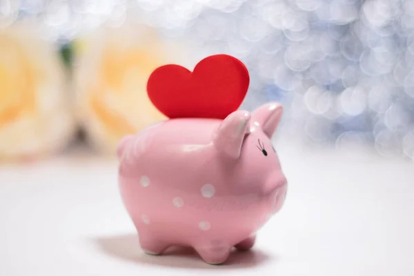 Pig piggy bank and heart on a blurred background. Love preservation concept.