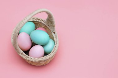 Paskalya dekoru: sepetteki renkli yumurtalar, pembe arka plan. Paskalya için hazırlanılıyor.