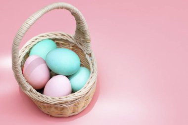 Paskalya dekoru: sepetteki renkli yumurtalar, pembe arka plan. Paskalya için hazırlanılıyor.