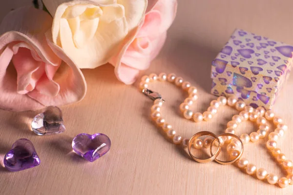 Wedding preparations. Two wedding rings, pearl beads, flowers and hearts.