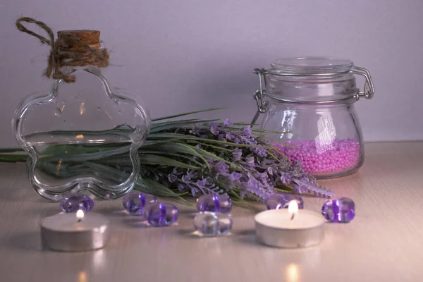 Glass jars, lavender bouquet and candles. Preparing for spa treatments.
