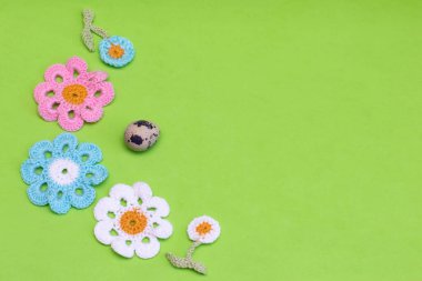 Yeşil arka planda örülmüş dekoratif çiçekler ve bıldırcın yumurtası. Paskalya tatili için dekorasyon, kopyalama alanı.