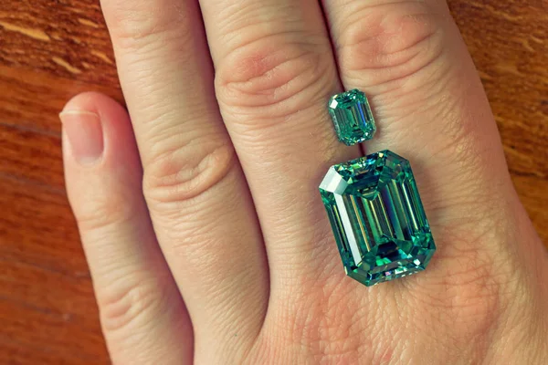 Hand with green emerald gemstones