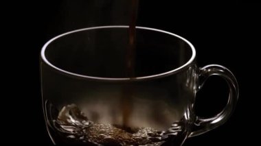 Siyah arkaplandaki bardaklara çay dökülüyor