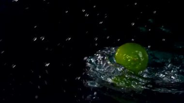 Siyah zemin üzerinde suyla sıçrayan taze limonlara yakın çekim 