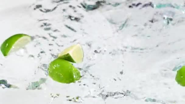 Zbliżenie Świeżych Limonek Rozbryzganych Wodą Białym Tle — Wideo stockowe