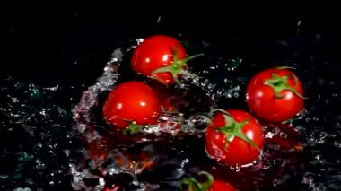 Kiraz domatesleri ve siyah arka planda su. Yemek konsepti. Boşluğu kopyala.