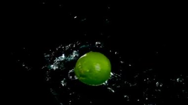 Siyah zemin üzerinde suyla sıçrayan taze limonlara yakın çekim 