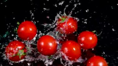 Kiraz domatesleri ve siyah arka planda su. Yemek konsepti. Boşluğu kopyala.