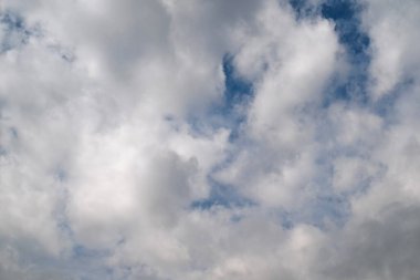 Gökyüzü bulutlu ve güneş bulutların arasında parlıyor. Gökyüzü mavi ve bulutlar beyaz