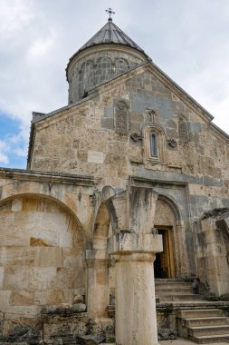 Çan kulesi ve haçı olan bir Haghartsin Manastırı. Bina eski ve üzerinde çok fazla detay var. Gökyüzü bulutlu ve güneş görünmüyor.