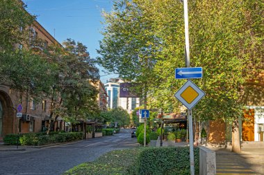 Erivan, Ermenistan 10.16.2025. Sağını gösteren mavi oklu bir cadde. Arka planda birkaç ağaç ve bina var.