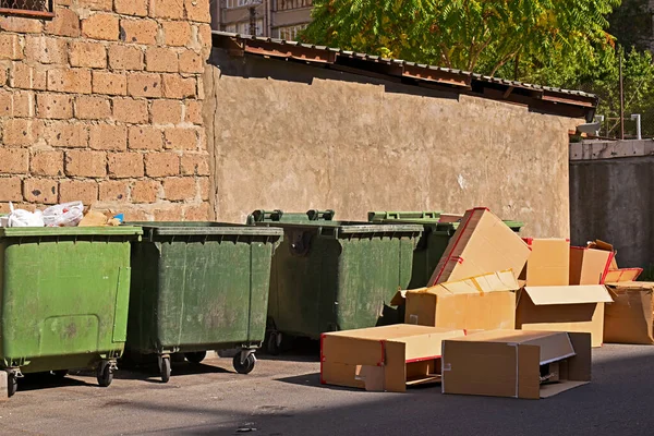 Bir çöp yığını tuğla duvarın önünde duruyor. Çöpte yeşil bir kutu, bir karton kutu ve bir yığın başka çöp var. İhmal ve düzensizlik kavramı