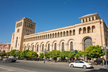 Erivan, Ermenistan 10.16.2025. Önünde kemerli camlar ve beyaz bir araba olan büyük bir bina. Bina bir otel ya da büyük bir ofis binası gibi görünüyor. Araba yolun kenarına park edilmiş.