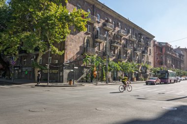 Erivan, Ermenistan 10.16.2025. Bir adam bir binanın önündeki caddeden aşağı bisiklet sürüyor. Sokaklar arabalar ve otobüsle dolu.