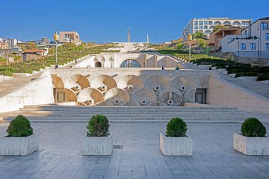 Erivan, Ermenistan 10.16.2025. Arkasında beyaz bir bina olan büyük bir avlu. Avlu saksı bitkileriyle çevrili ve taş zemini var.