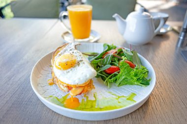 Bir tabak yemek, sahanda yumurta ve salata. Tabak ahşap bir masanın üzerinde.