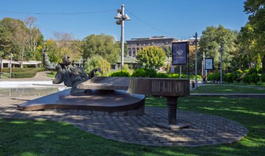 Erivan, Ermenistan 10.16.2025. Piyano çalan bir Arno Babajanyan heykeli bir parkta. Heykel bir tuğla geçit ve göl ile çevrilidir.