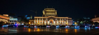 Erivan, Ermenistan 10.16.2025 Cumhuriyet Meydanı. Geceleri arka planda büyük bir bina olan bir şehir caddesi. Sokaklar arabalarla dolu ve binanın ışıkları ve sokak lambaları sıcak ve davetkar bir atmosfer yaratıyor.