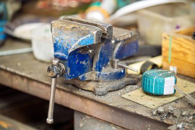 Bir şeyleri yerinde tutmak için kullanılan mavi bir alet. Kirli ve üzerinde çok pas var.