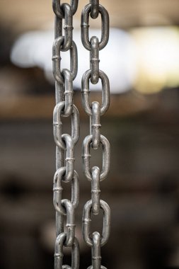 Gümüş halkalar zinciri yakın planda gösterilir. Zincir uzundur ve metalik görünümlüdür.