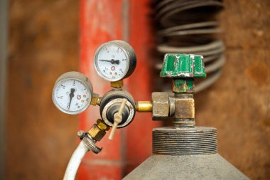 Basınç göstergesi bir oksijen tüpüne bağlıdır. Gösterge yeşil ve beyaz. Konteynır kırmızı.