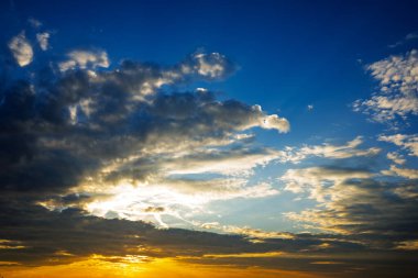 Gökyüzü birkaç bulutla mavidir. Güneş batıyor ve gökyüzü ılık turuncu bir renkle parlıyor.