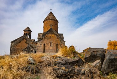 Çan kulesi ve haçı olan bir Ermeni Saghmosavanq manastırı. Bina kayalar ve otlarla çevrili.