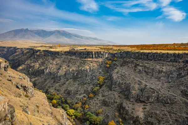 İçinden nehir akan bir dağ sırası. Dağlar ağaçlarla kaplı ve nehir kahverengi.
