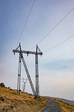 Tepesinde bir hava istasyonu olan uzun bir elektrik direği. Gökyüzü açık ve güneş parlıyor.