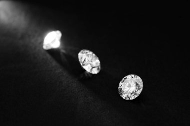 Siyah arka planda üç elmas var. Elmaslar parlak ve pırıltılı. Görüntünün karanlık ve gizemli bir havası var.