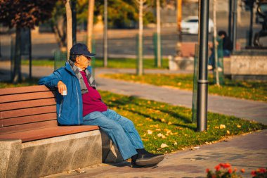 Yaşlı bir adam parkta bir bankta oturuyor. O, mavi bir ceket ve bir şapka giyiyor. Park bomboş ve etrafta başka kimse yok. Adam parkın huzurlu atmosferinin tadını çıkarıyor.