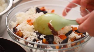 Bir kadın Ermeni yemeği hazırlamak için pirinç ile kurutulmuş meyveyi karıştırıyor.