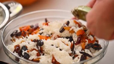 Bir kadın Ermeni yemeği hazırlamak için pirinç ile kurutulmuş meyveyi karıştırıyor.