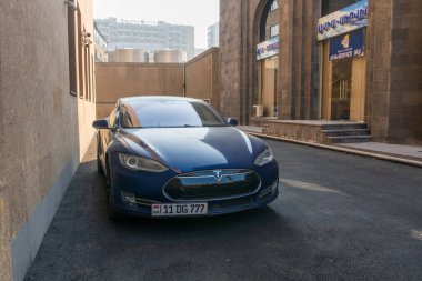 Erivan Ermenistan 10.25.2025. Bir binanın önüne park edilmiş mavi bir Tesla. Arabanın plakasında 11DG77 yazıyor.