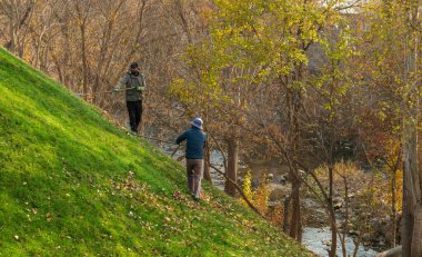 Erivan Ermenistan 10.25.2025. İki kişi ormanda bir tepeye tırmanıyor. Soldaki adam mavi bir ceket giyiyor.
