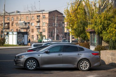 Gümüş renkli bir araba bir binanın önünde park edilmiş. Araba bir binanın yanındaki otoparkta park halinde.