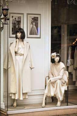 Erivan Ermenistan 12.7.2025. İki manken bir mağazanın vitrininde oturuyor, biri beyaz elbiseli, diğeri beyaz önlüklü.