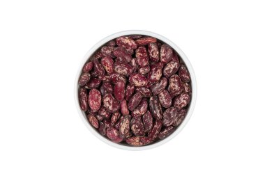 Beyaz arka planda bir kase kırmızı fasulye var. Fasulyeler farklı boyutlarda ve kasenin her tarafına saçılmış.