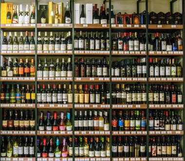 Raflarda bir sürü şarap şişesi olan bir şarap dükkanı. Şişeler farklı renk ve boyutlarda.