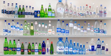 Farklı renkler ve tasarımlarla dolu bir raf. Şişeler sıra sıra diziliyor ve bazı şişeler diğerlerinden daha uzun oluyor. Renklerin çeşitliliği