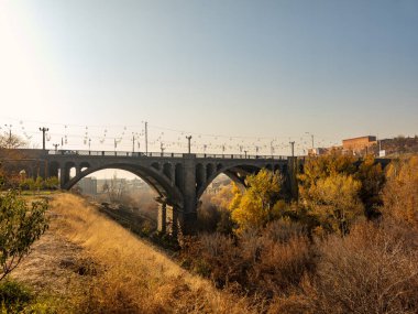 Erivan 'daki Pobeda köprüsünün altından tren geçen bir nehir geçmektedir. Köprü eski ve kırsal bir görünüme sahip. Tren kullanımda değil ve köprü de boş. Gökyüzü açık ve güneş parlıyor.