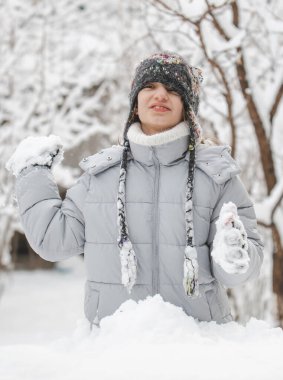 Gri paltolu ve şapkalı bir kız çocuğu kartoplarıyla oynuyor.