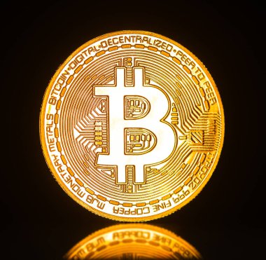 Üzerinde B harfi olan altın bir bitcoin. Para parlak ve yansıtıcı bir yüzeyi var.