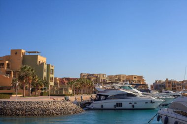 El Gouna Mısır 'da açık mavi gökyüzü olan bir marinaya bir grup tekne yanaştı. Tekneler çeşitli boyut ve renklerde ve marina binalarla çevrili. Boş zaman ve rahatlama kavramı