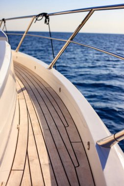 Teknenin yanında ahşap korkuluklu ve gümüş parmaklıklı bir tekne.