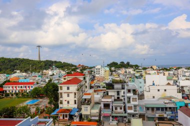 İzlanda Phu Quoc Vietnam 5.7.2025. Bir sürü binası ve büyük kırmızı çatısı olan bir şehir manzarası. Gökyüzü bulutlu ve güneş parlıyor