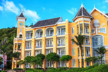 Saat kulesi ve balkonu olan sarı bir bina. Binanın üst katında bir sürü pencere ve balkon var.